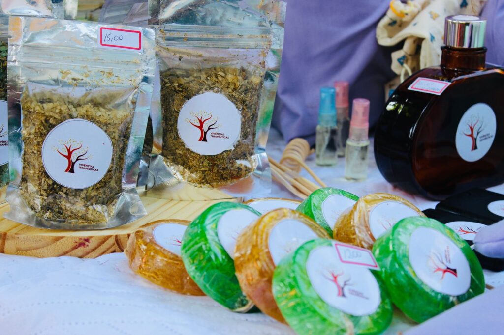 Foto de uma mesa com produtos orgânicos: saquinhos de temperos, sabonetes artesanais, vidro com perfume. 